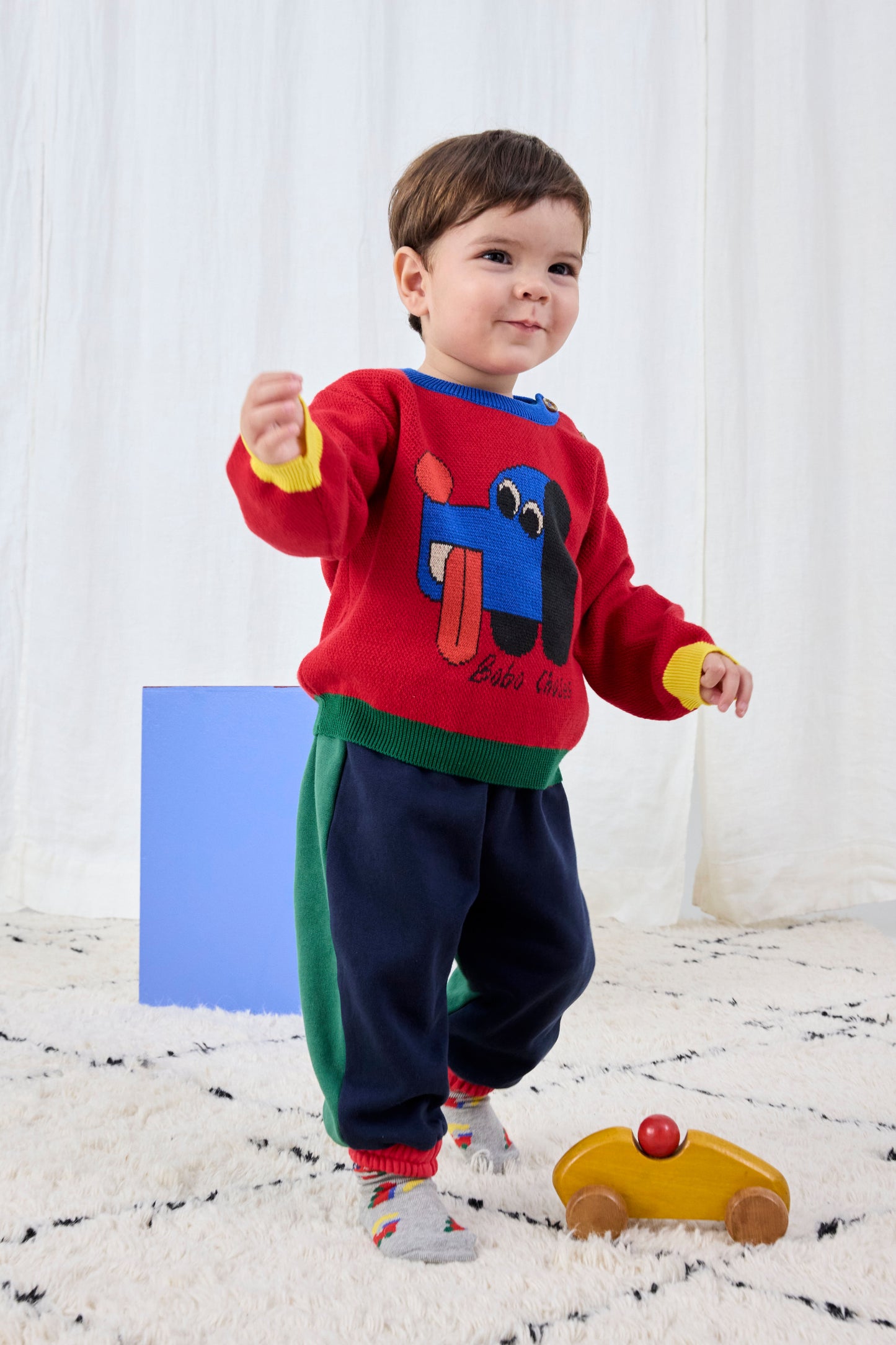 Child wearing a colorful sweater with a dog design on a white background