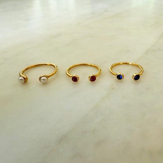 Three gold nose rings with gemstones on a light background