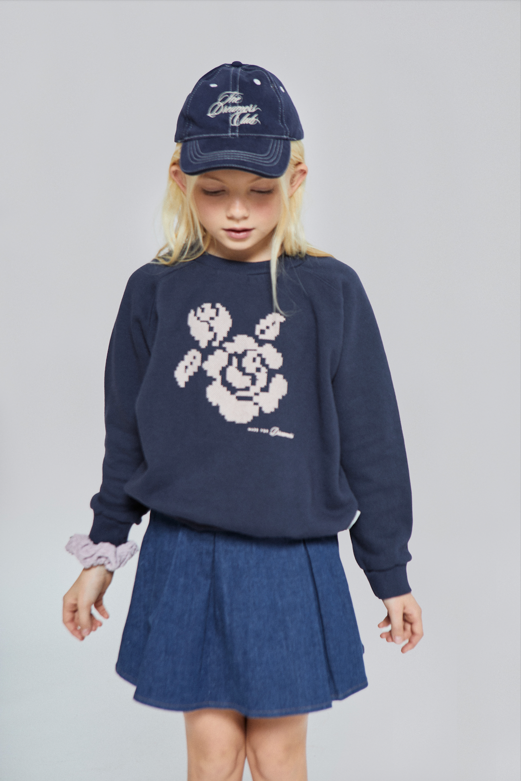 Child wearing a navy sweater with floral design and matching skirt on a plain background