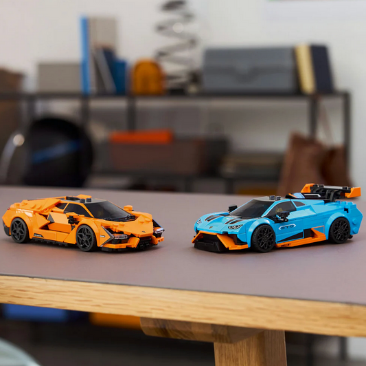 Two toy cars, one orange and one blue, on a table with a blurred background.