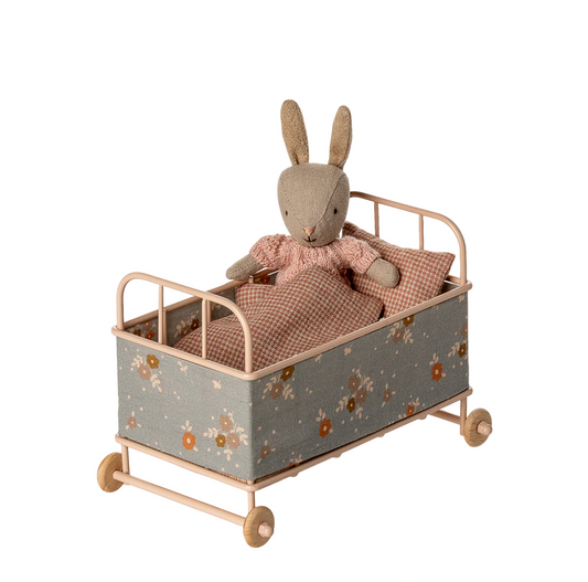 Toy rabbit in a small bed with floral pattern on a white background