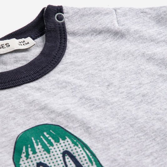 Gray shirt with green dinosaur design and navy collar, brand label visible.