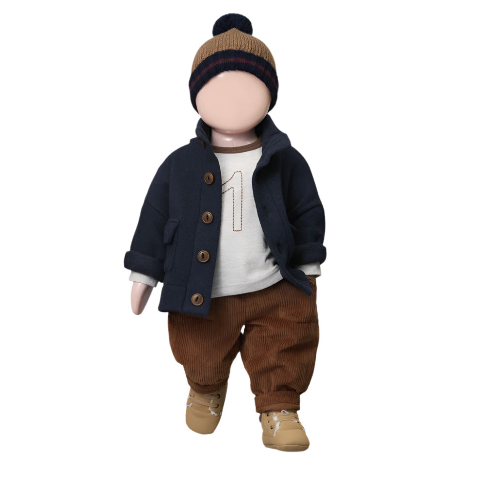 Toy figure of a child wearing a navy coat, brown pants, and a knit hat on a white background