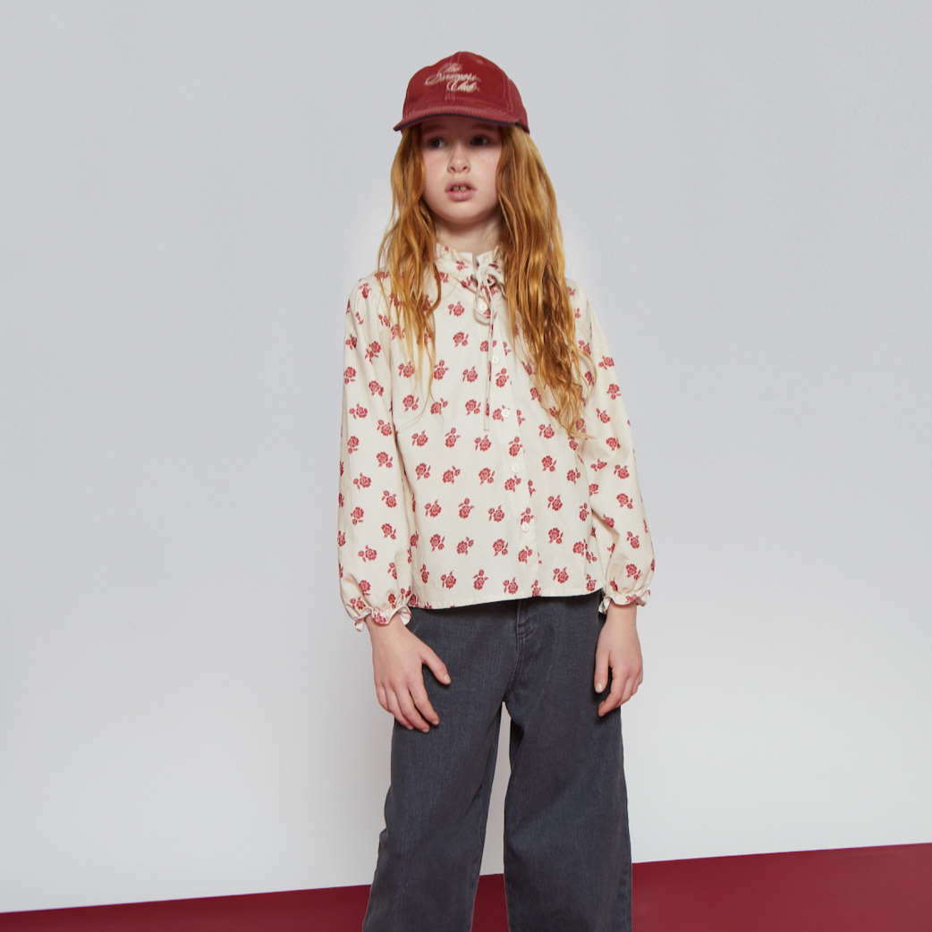 Person wearing a floral shirt, dark pants, and a red cap on a white and red floor.
