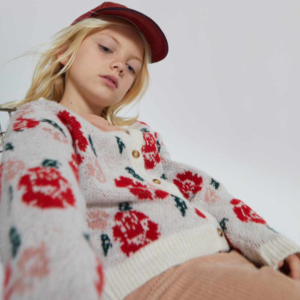 Person wearing a floral sweater and red cap on a plain background