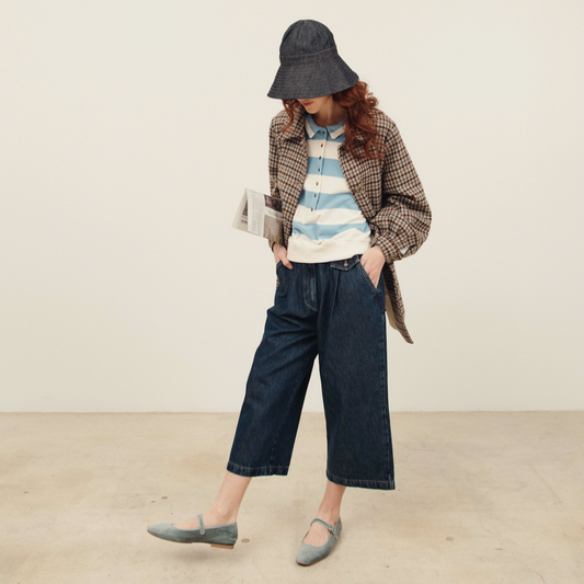 Person wearing a plaid jacket, striped shirt, and wide-leg jeans against a plain background