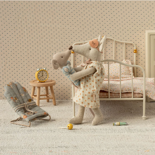 Stuffed elephant toy in a child's bedroom with a bed, chair, and clock.