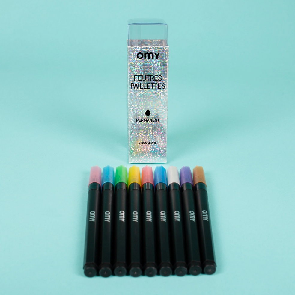 Set of colorful markers with a packaging box on a light blue background