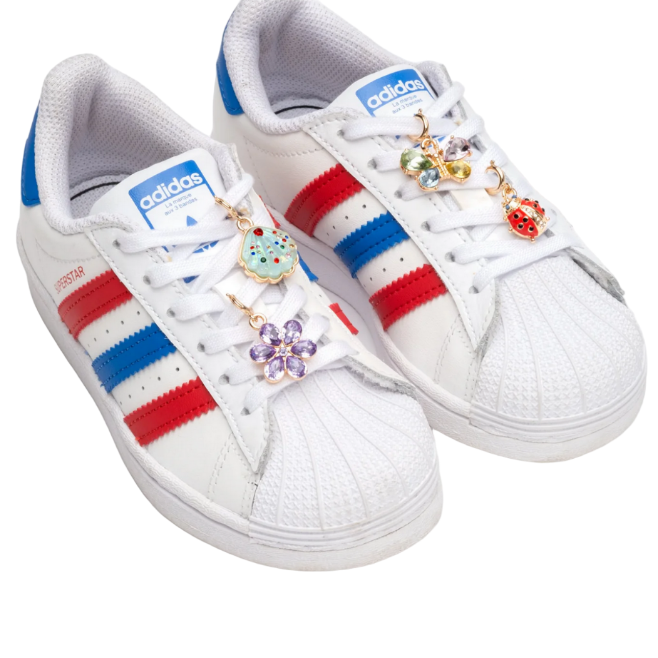 White Adidas sneakers with red and blue stripes and decorative charms on a white background