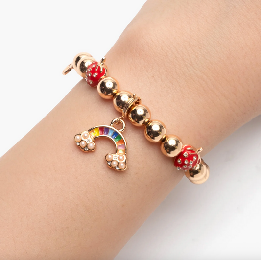 Bracelet with gold beads and a rainbow charm on a wrist against a white background