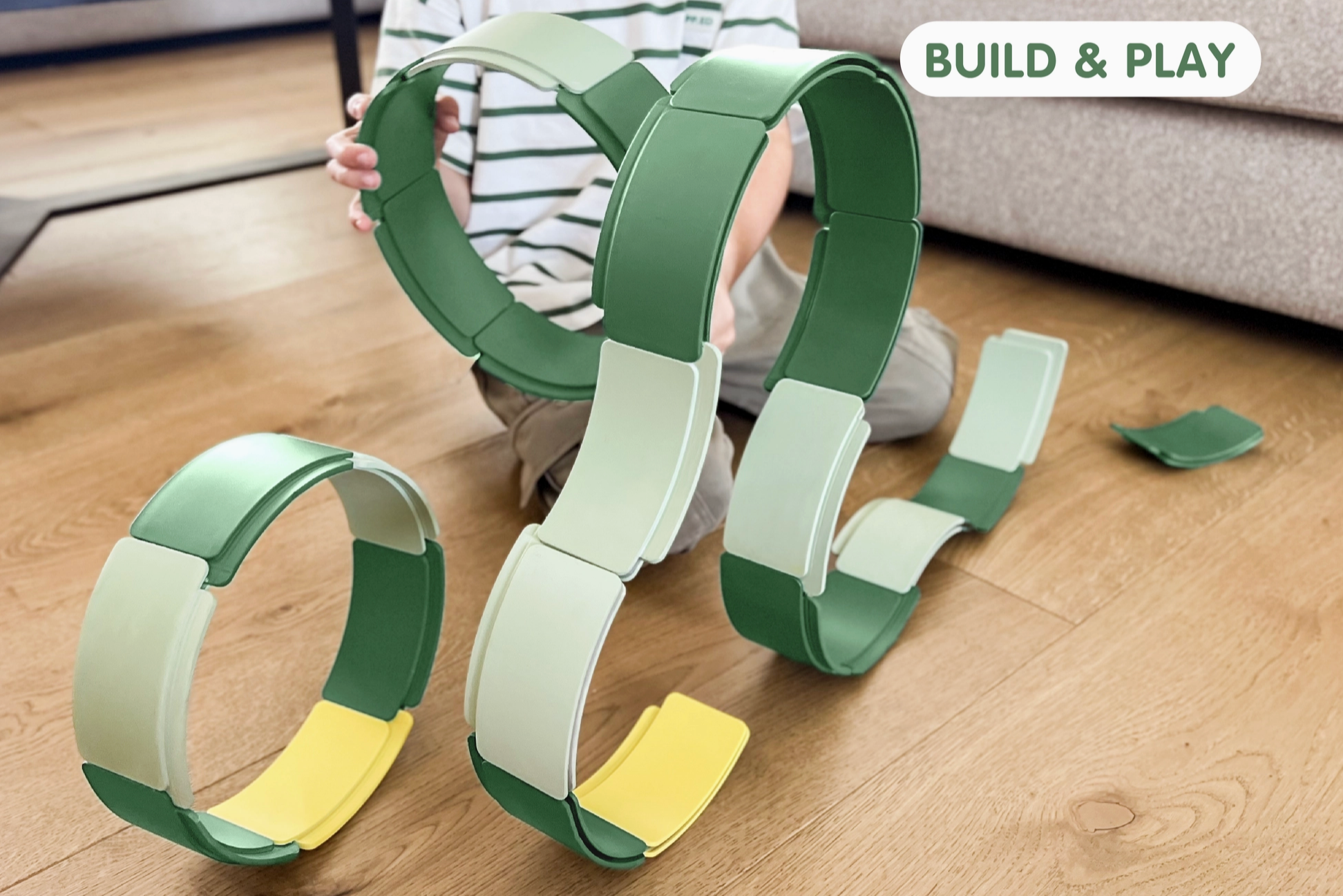 Children's building toys on a wooden floor with 'Build & Play' text.