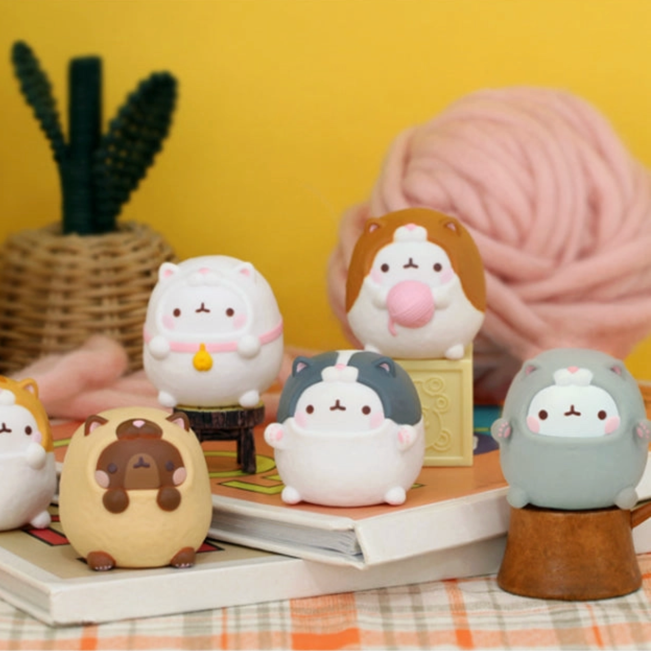 Set of cute animal-themed figurines on a table with a yellow wall and plant in the background.