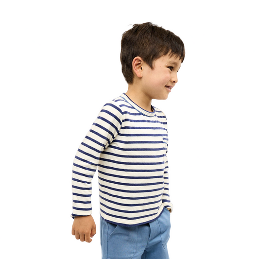 Child wearing a striped shirt and blue pants on a white background