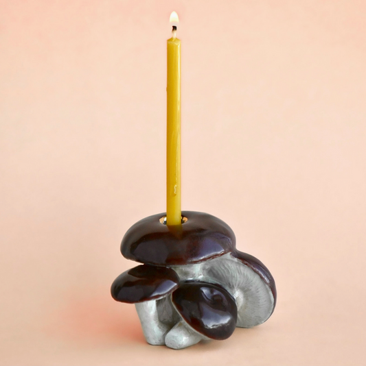 Ceramic candle holder with a yellow candle on a beige background