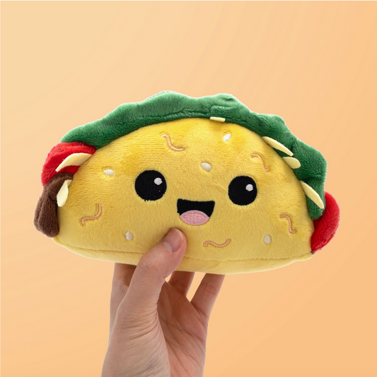 Plush taco toy held by a hand against a beige background