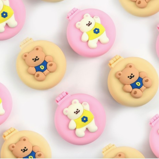 Small bear-shaped containers with pink and beige lids on a white background