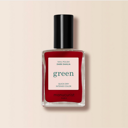 Red nail polish bottle with a black cap on a beige background