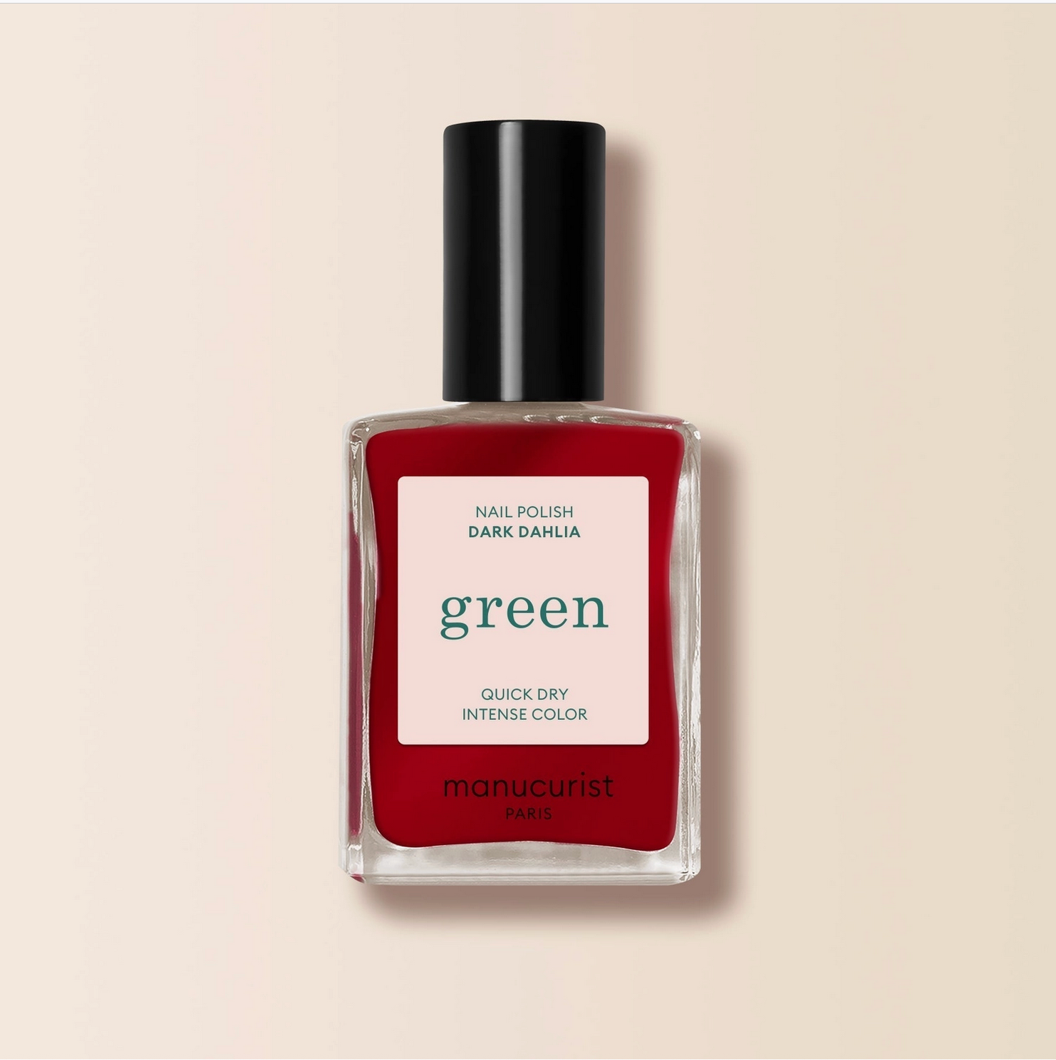 Red nail polish bottle with a black cap on a beige background