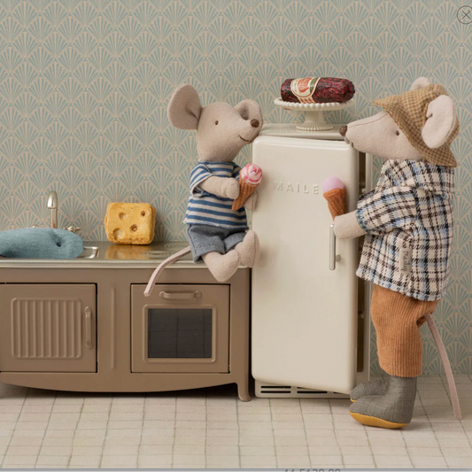 Two toy mice in a kitchen setting with a refrigerator and sink.