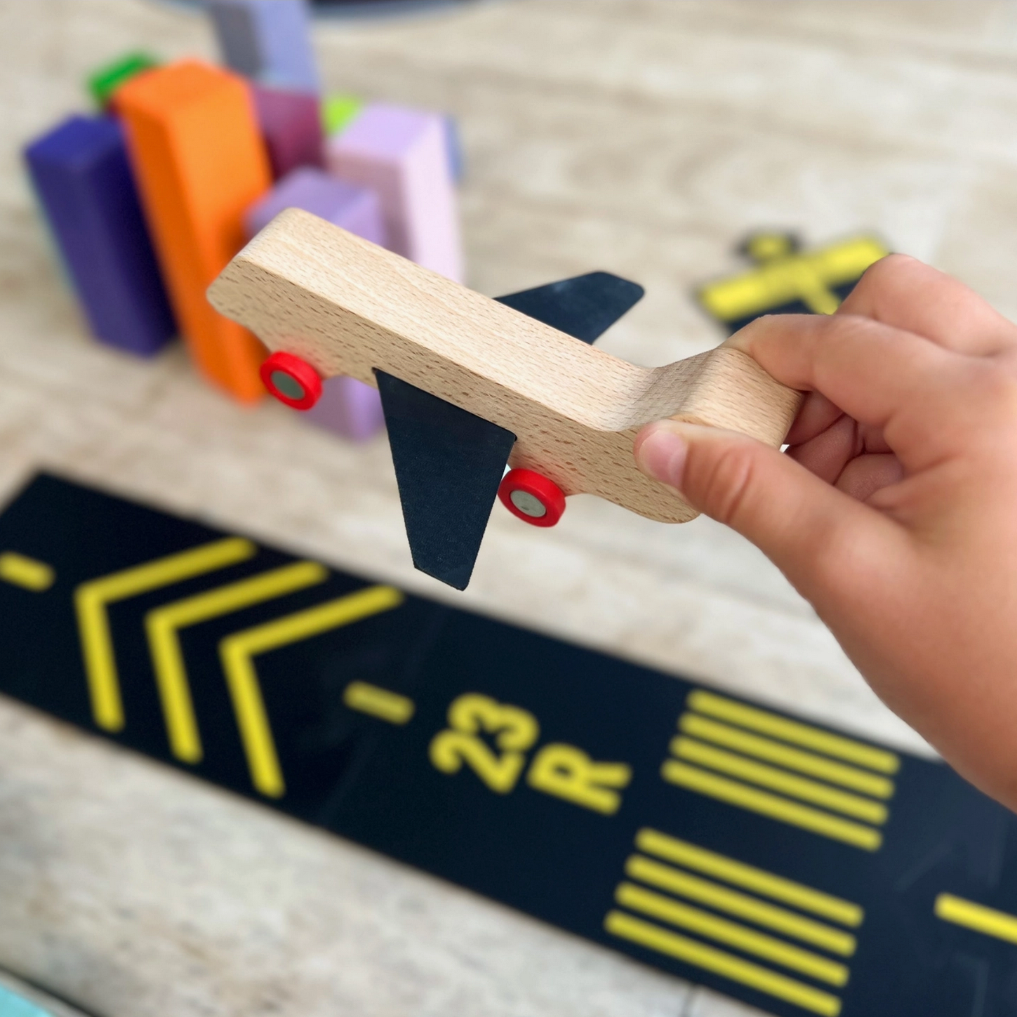 Hand holding a wooden toy block on a game board with colorful blocks in the background