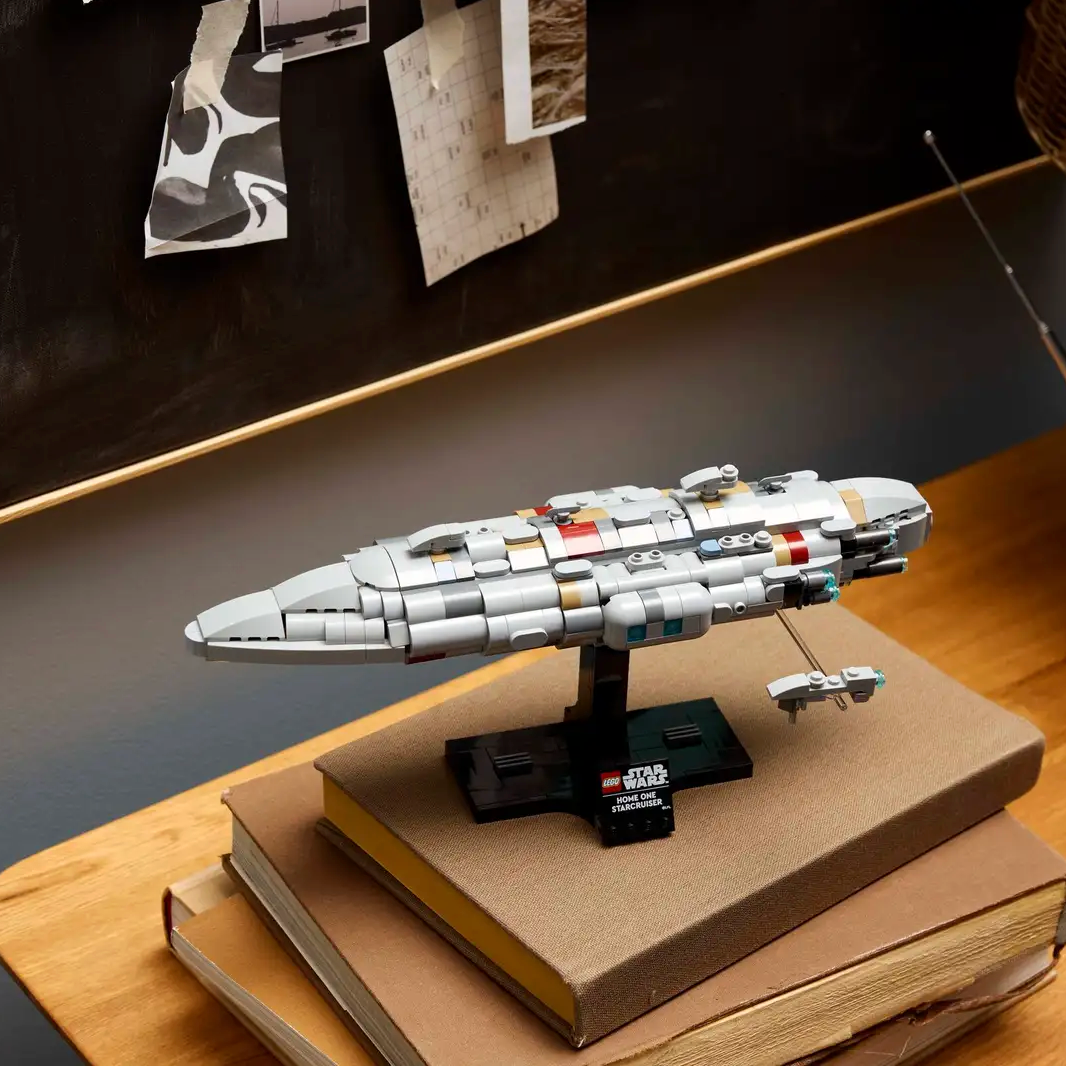 Model spaceship on a stand on top of books with a dark wall and lamp in the background