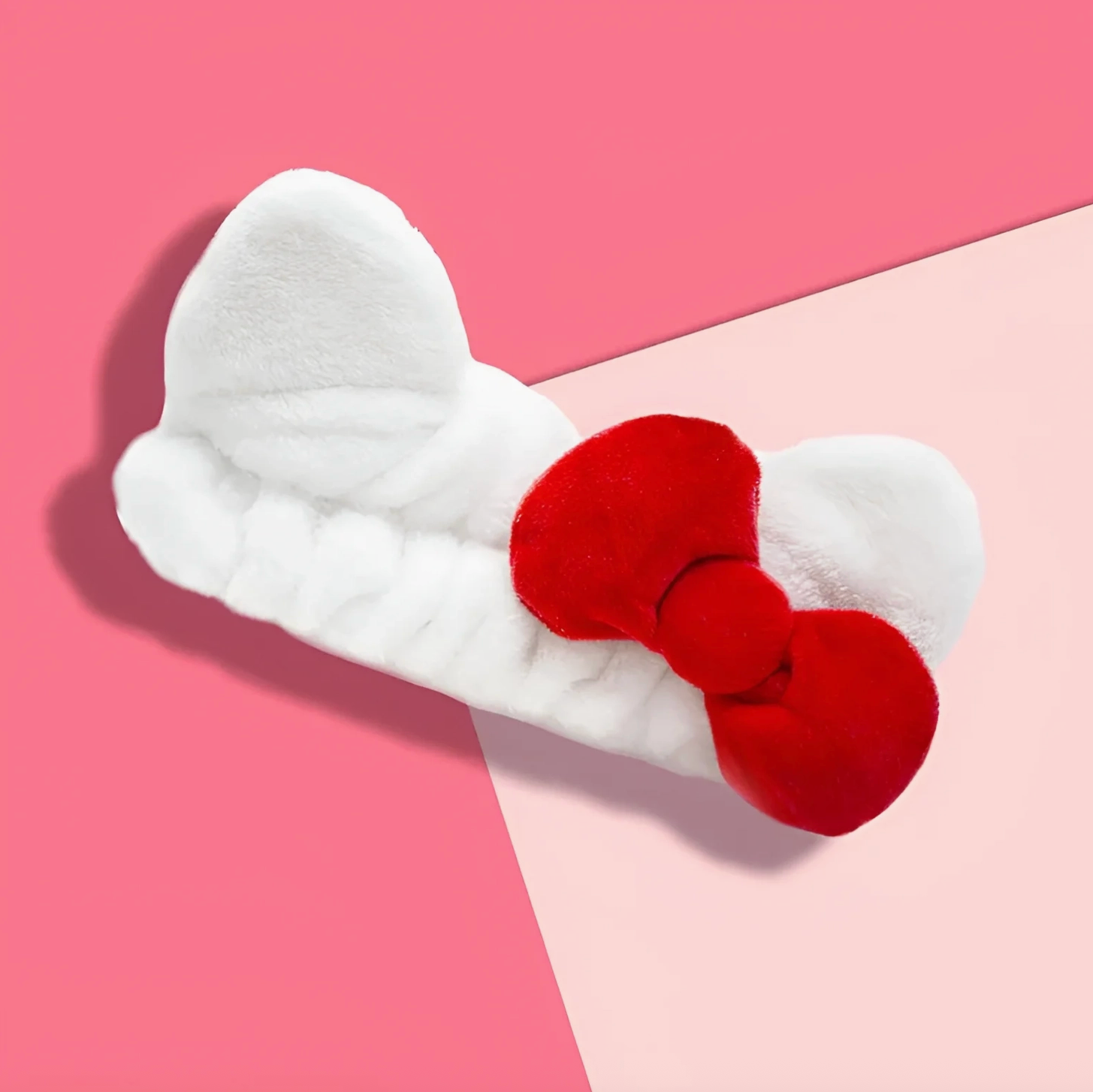 White bow-shaped hair clip with a red center on a pink background