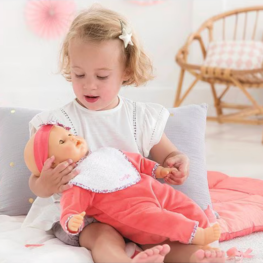 Child playing with a doll on a soft surface with a blurred background