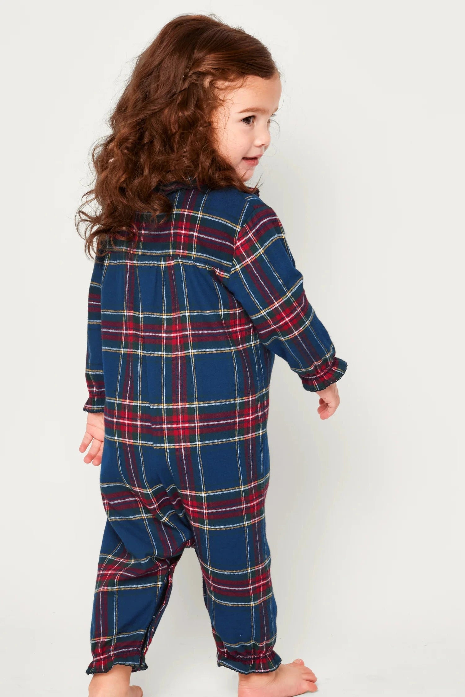 Child wearing a blue plaid onesie against a white background
